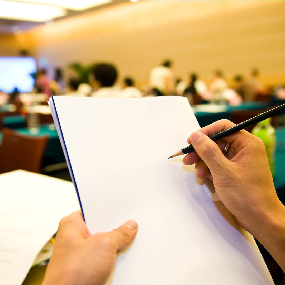 mani che scrivono su un quaderno durante un seminario o workshop