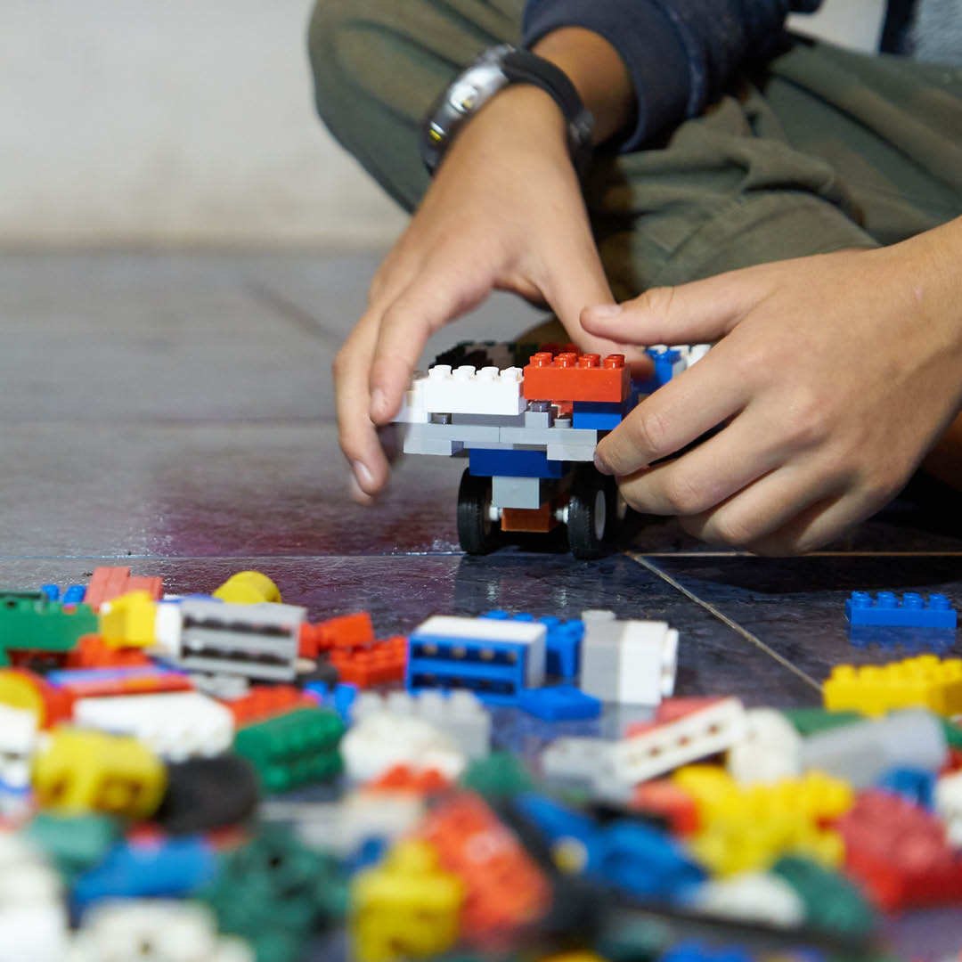 Le mani di una persona che sta giocando con alcuni pezzi colorati di LEGO®