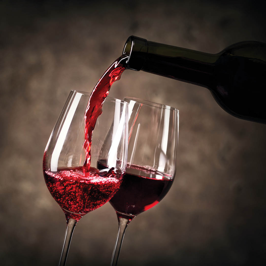 Una bottiglia versa del vino rosso in due calici da vino
