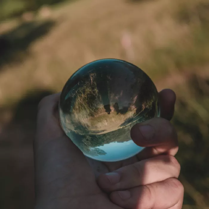 Mano con in mano una sfera che riflette il mondo