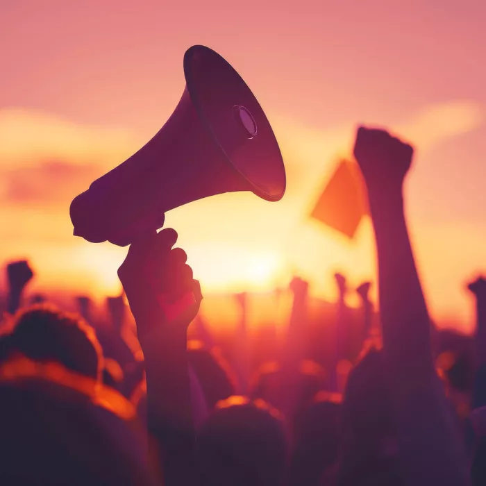 Mani di manifestanti e di un megafono in controluce 
