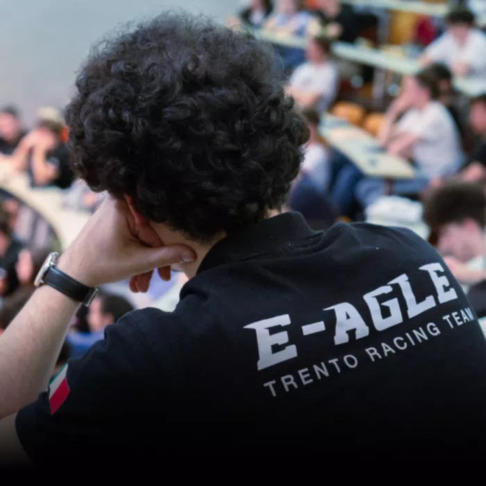 Studente di spalle che indossa una maglietta nera con logo "E-Agle Trento Racing Team" segue un seminario